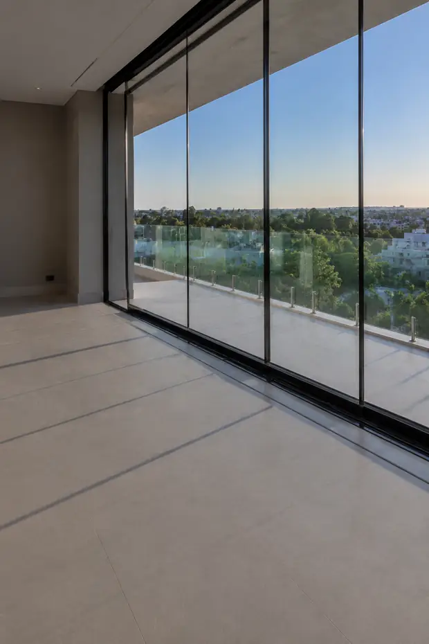 Varanda envidraçada com perfil preto e vista para as árvores